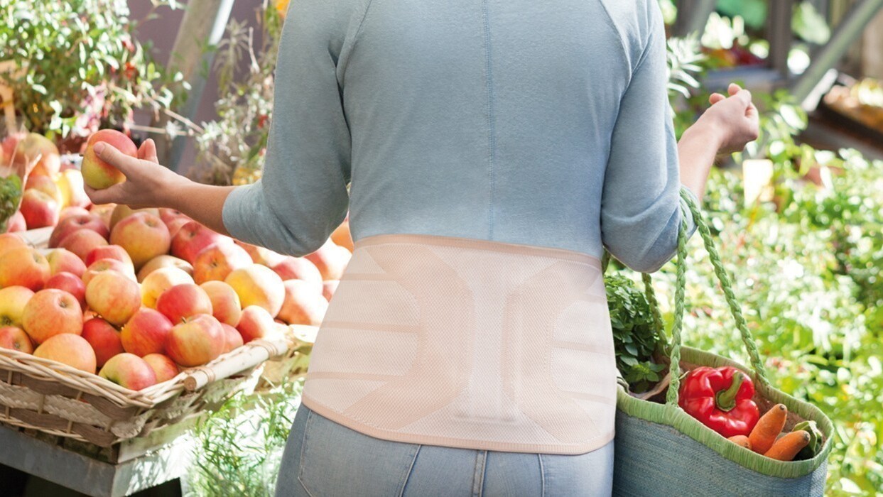 Woman in a supermarket wearing a back brace Woman in a supermarket wearing a back brace