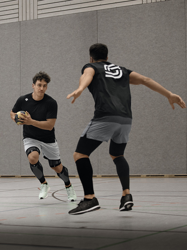 Sportomedix Compression Sleeves Zwei Männer spielen Handball in der Halle