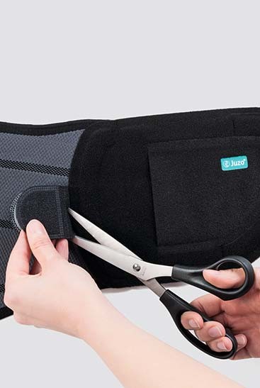 4th product image Cut to size JuzoPro Lumbal Plus with scissors shows how straps can be shortened as required