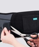 4th product image Cut to size JuzoPro Lumbal Plus with scissors shows how straps can be shortened as required