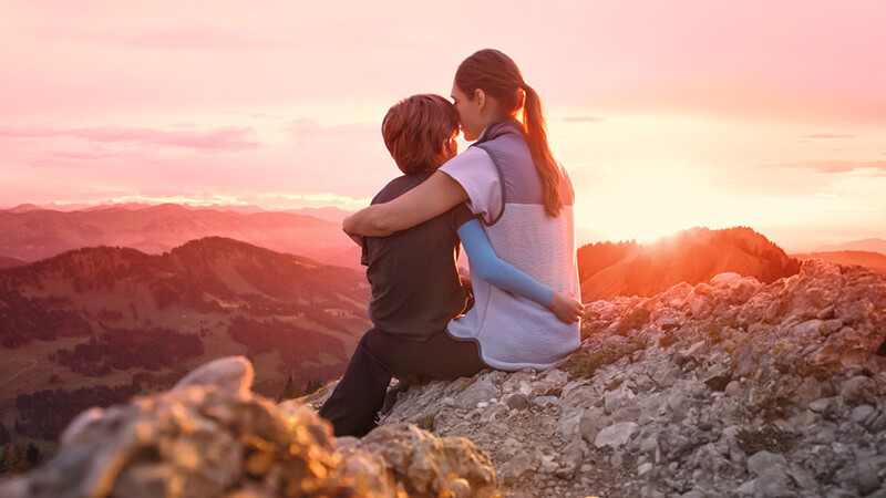 Una madre está sentada con su hijo en la cima de una montaña. El niño lleva una manga de compresión. Una madre está sentada con su hijo en la cima de una montaña. El niño lleva una manga de compresión.
