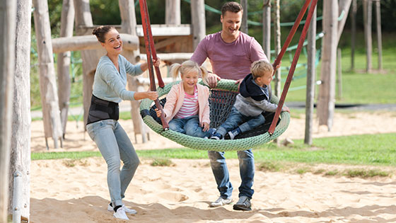 A family at the playground. The children are on the swings. The mother is wearing a back brace A family at the playground. The children are on the swings. The mother is wearing a back brace