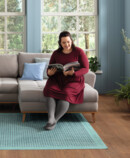Woman sitting on her couch, smiling and reading a magazine